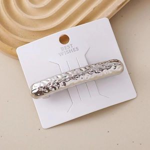 Detailed view of silver hair clip with hammered texture on white display card