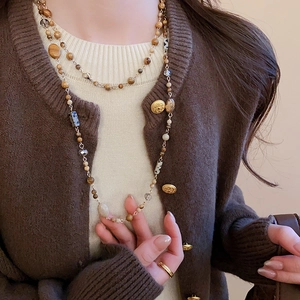 Close-up of a vintage geometric beaded necklace featuring earth-toned stones and gold plating