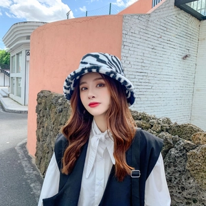 Close-up of zebra pattern plush bucket hat styled with a vest in a city street setting
