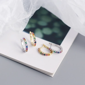Macro shot of S925 silver U-shaped hoops in gold and silver with rainbow gemstones