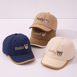 Détails des motifs d'ours brodés et des bordures contrastées sur casquettes enfant en coton