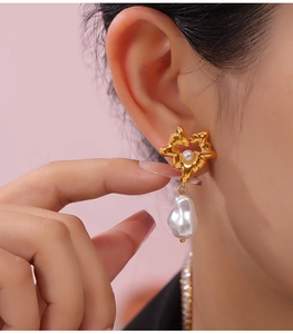 Detailed close-up of a vintage gold heart pearl earring worn by a female model