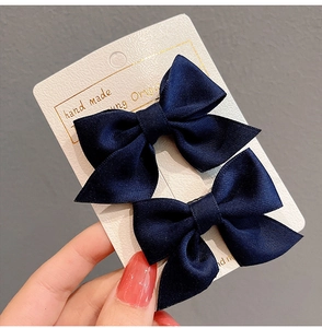 Detail showing two navy blue bow hair clips on a white handmade display card
