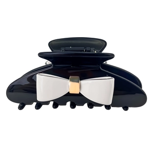 Elegant black acetate hair claw clip with large white bow and gold metal accent