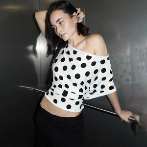 Detail of off-shoulder slim fit white top with large black polka dot pattern for women