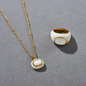 Macro detail of 18k gold plated necklace and ring set with lustrous white mother of pearl