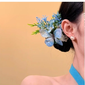 Pince à cheveux élégante avec papillon bleu en tissu et fleurs sur un chignon