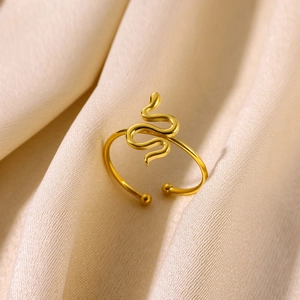 Detailed macro view of an adjustable gold-toned snake ring on beige satin fabric