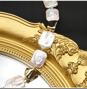 Macro shot of baroque square pearl necklace with golden metal accents on gold frame