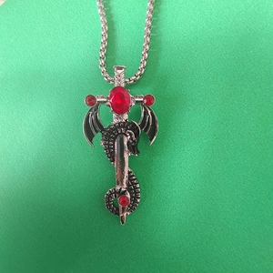 Détail du pendentif dragon et épée avec pierres rouges et finition argentée