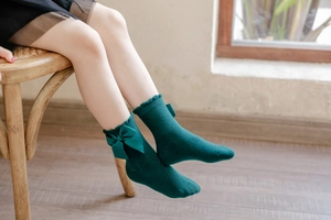 Close-up of dark green cotton knit princess socks with silk bow and ruffled edges