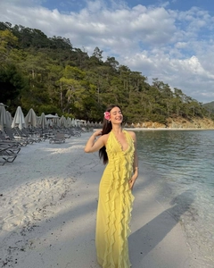 Full-length view of yellow chiffon maxi dress with ruffles on a tropical beach