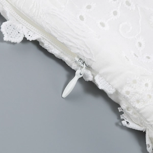 Detail of white hollow embroidery fabric with a concealed zipper for an elegant dress