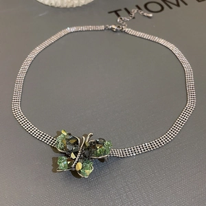 Macro shot of silver mesh chain necklace with detailed green crystal butterfly pendant