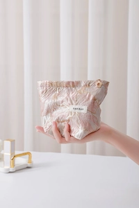 Close-up of pink jacquard makeup bag with floral patterns and a gold flower zipper pull