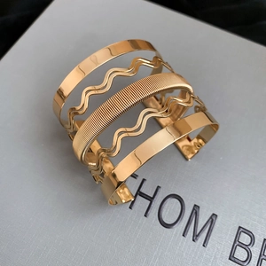 Macro detail of gold multi-layer wavy hollow cuff bracelet with textured metallic layers