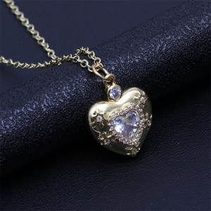 Macro shot of gold heart pendant with micro-pave cubic zirconia on textured black background