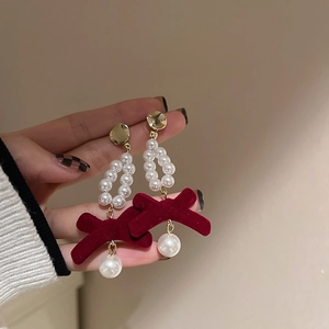 Detail of velvet wine red bow earring with white pearls and gold needle for women