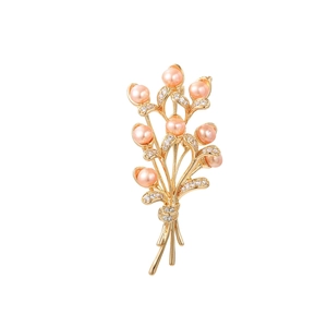 Detailed close-up of golden floral brooch with pink freshwater pearls and crystals