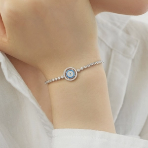 Detail of S925 sterling silver evil eye bracelet with blue and white gems on model wrist