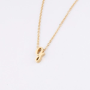 Vue détaillée d'un pendentif lettre g minuscule dorée en cursive sur une chaîne en métal