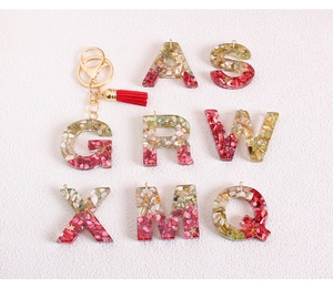 Detail of resin alphabet charms with glitter, sea shell flakes and colorful tassels