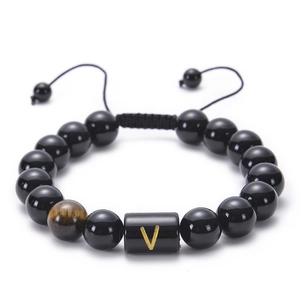 Detail of hand-woven black agate bead bracelet featuring a golden letter V charm and tiger eye