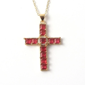 Close-up of gold-plated cross pendant featuring square-cut red zircon and white diamond accents
