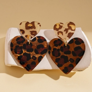 Detail of vintage acrylic leopard print heart earrings on a minimalist white stand