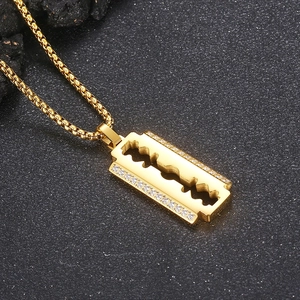 Detail shot of 18K gold plated blade pendant with CNC set white zircons on stone surface