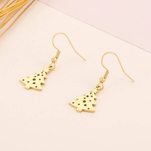 Close-up of golden stainless steel Christmas tree earrings on a soft pink background