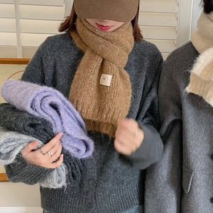 Detail of soft wool blend scarf featuring the EGG brand tag and brown knit texture