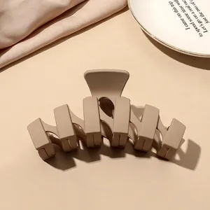 Close-up of a matte beige rectangular hair claw clip on a silk fabric background