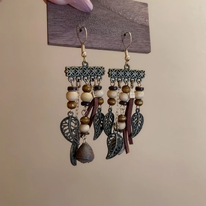 Detail of vintage bronze hoop earrings with wood beads and brown leather tassels