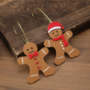 Close-up of brown felt gingerbread man ornaments with gold strings on wood background