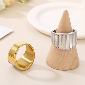 Detailed view of wide titanium steel rings with gold finish and white shell inlay