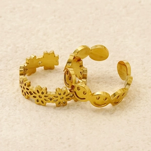 Detail of adjustable golden stainless steel rings with hollow flower and smiley designs
