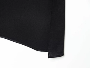 Détail de l'ourlet de chemise noire asymétrique avec texture sergée et coutures