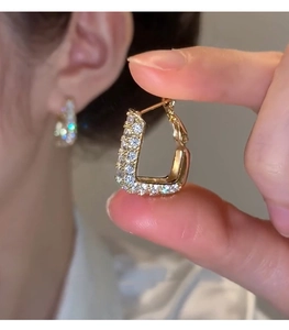 Close-up of golden U-shaped geometric earrings with sparkling pavé cubic zirconia
