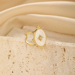 Close-up of gold oval mother of pearl ring with star pattern on stone slab