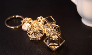 Detailed view of a gold geometric crystal keychain with hollow cubes on a leather surface