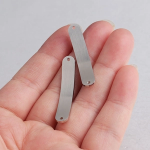 Macro detail of 6x35mm curved stainless steel bar connectors shown on a hand for scale