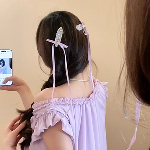 Detailed view of a purple ribbon bow hair clip with sparkling rhinestones on long tassels