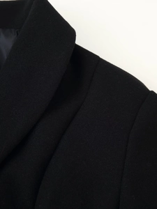 Detail of shawl collar and shoulder seams on a black wool coat with soft texture