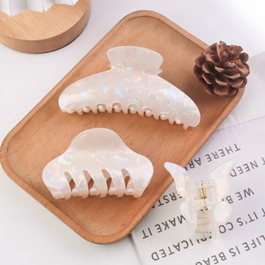 Elegant white iridescent hair claw clip set in various sizes on a rustic wooden tray