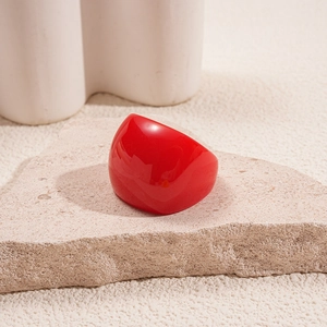Close-up of vibrant red resin ring with high-gloss finish on a beige textured stone