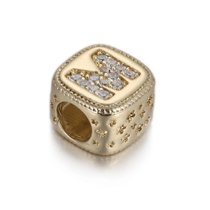 Dettaglio del charm lettera K dorato con zirconi micro-pavé e incisioni a stella