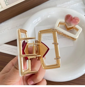 Detail of metal heart hair claw clips with white borders and strong gold-tone springs