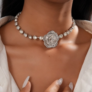 Gros plan du collier avec pendentif rose en cristal argenté porté par un mannequin