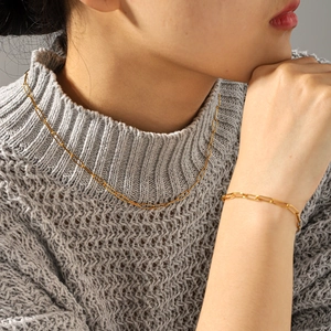 Gros plan du collier à chaîne dorée et bracelet assorti sur mannequin avec tricot